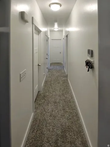 Hallway featuring light-toned plush carpet flooring