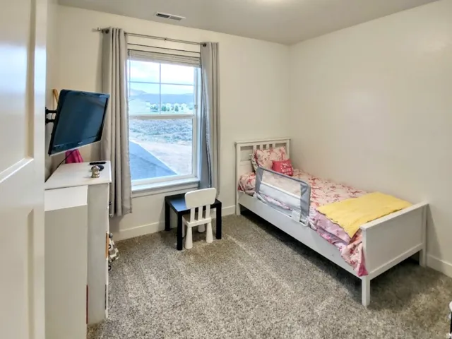 Bright room featuring a large window, neutral wall paint, and gray carpet flooring