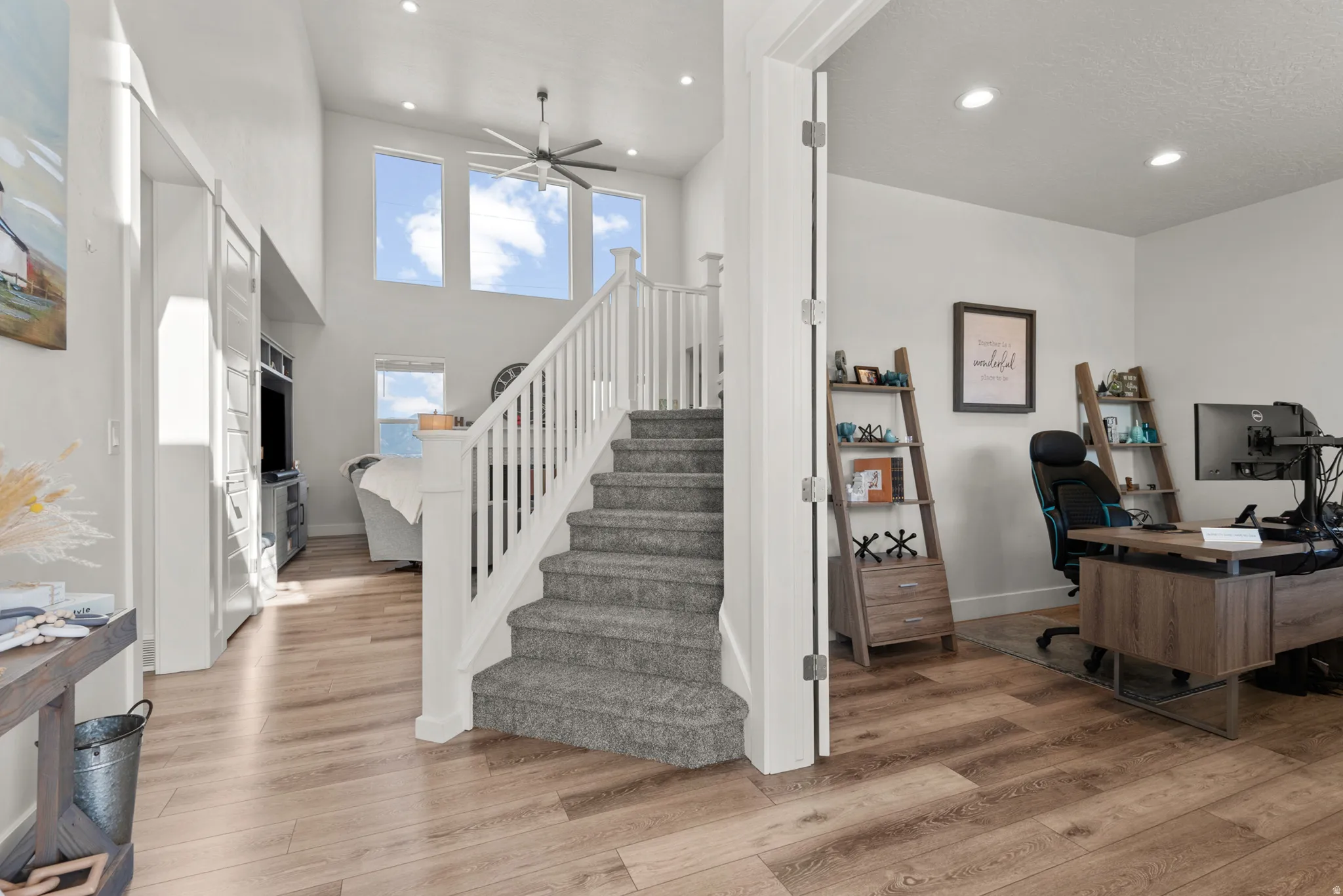 Grand entryway featuring a carpeted staircase with white balusters, wood-finish flooring, and high ceilings with transom windows