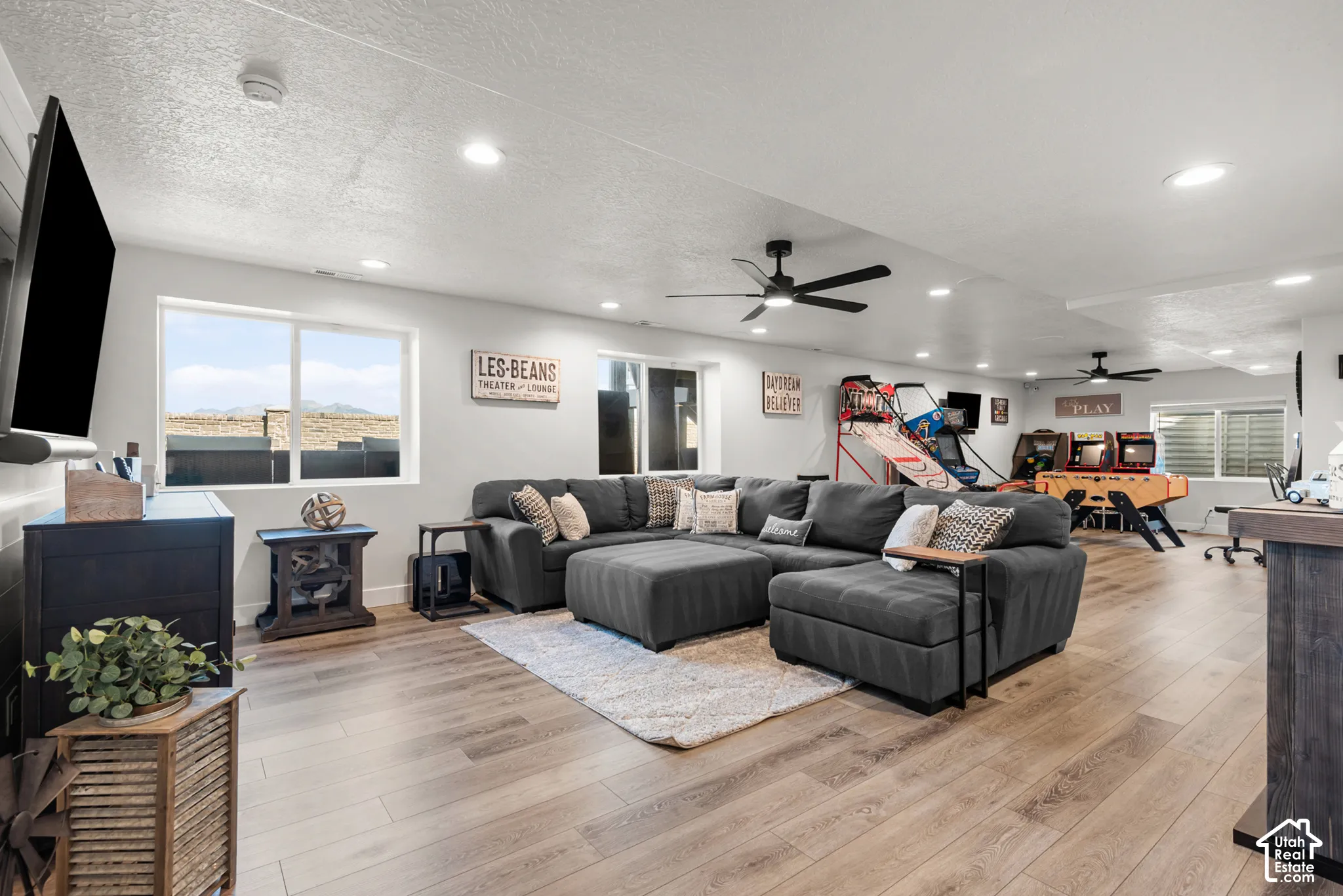 Spacious recreation room featuring light wood-finish flooring, recessed lighting, and multiple ceiling fans