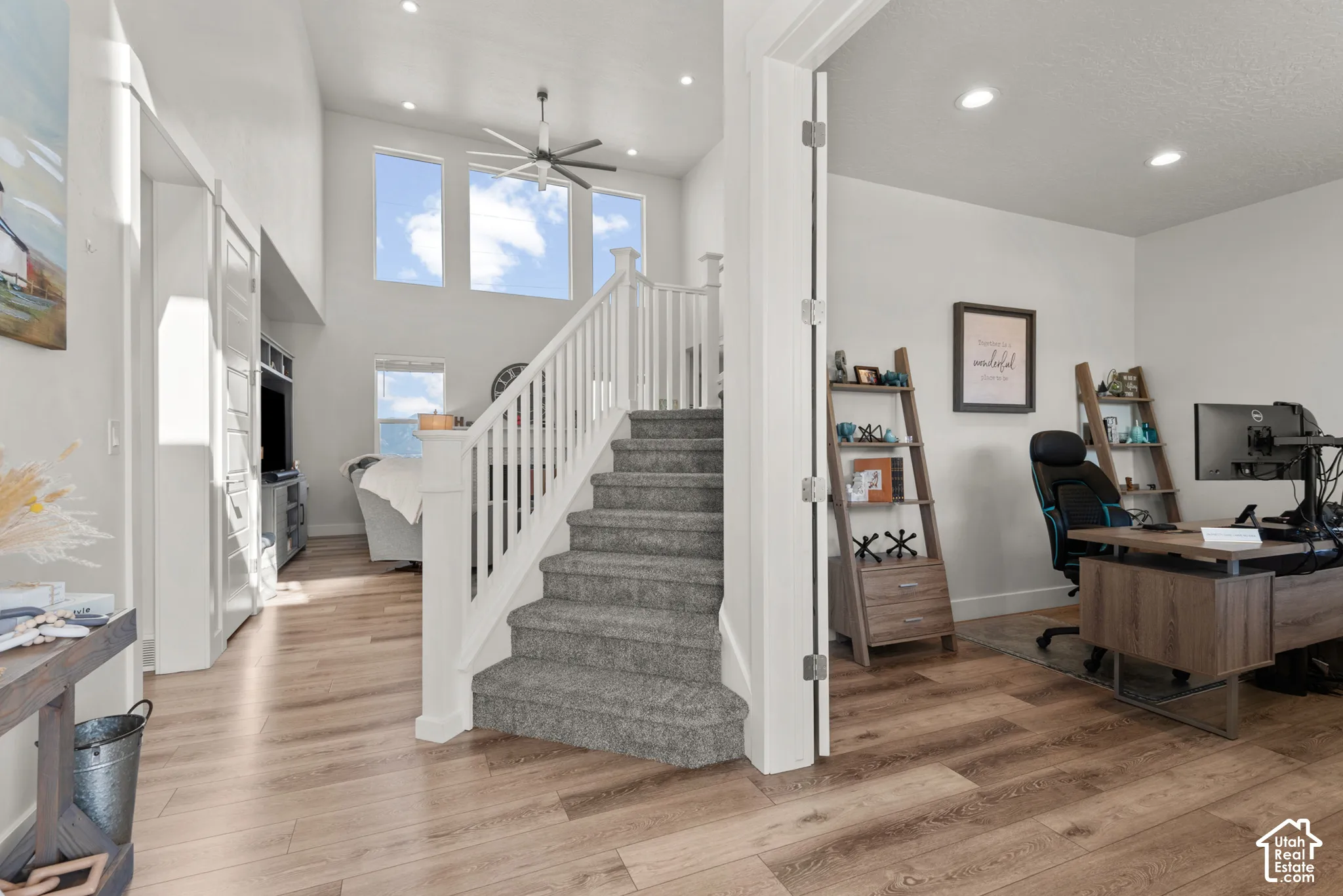 Grand entryway featuring a carpeted staircase with white balusters, wood-finish flooring, and high ceilings with transom windows