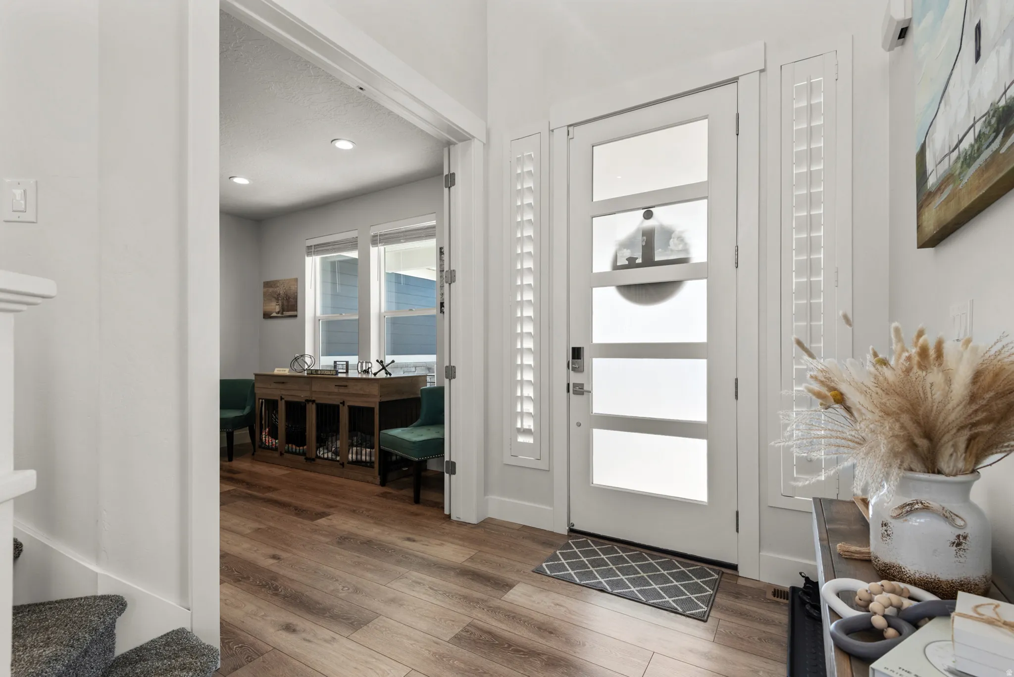 Entryway featuring wood-finish flooring, a contemporary door with frosted glass panels, and sidelight shutters