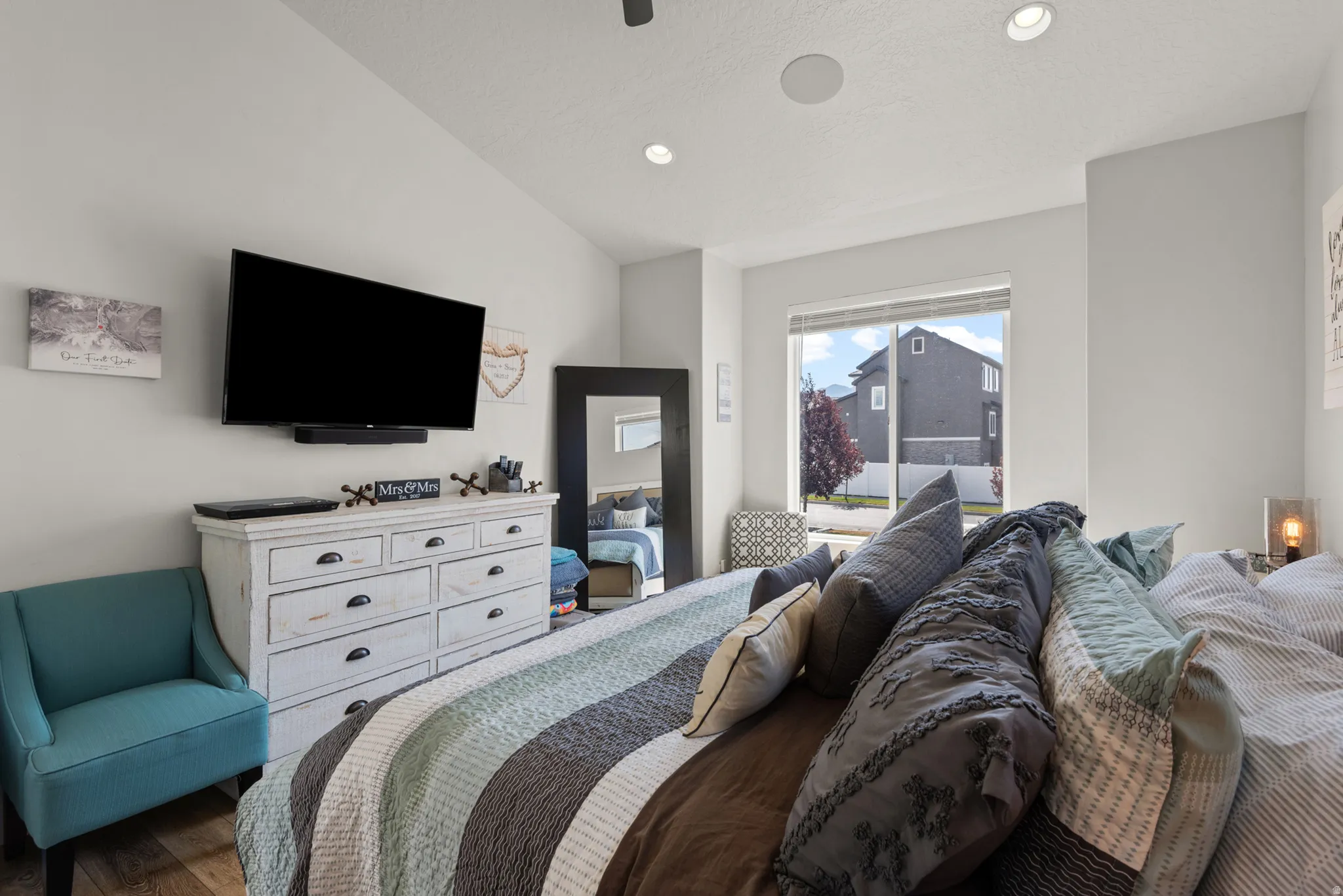 Spacious room featuring vaulted ceilings, recessed lighting, wood-finish flooring, and a large window offering ample light