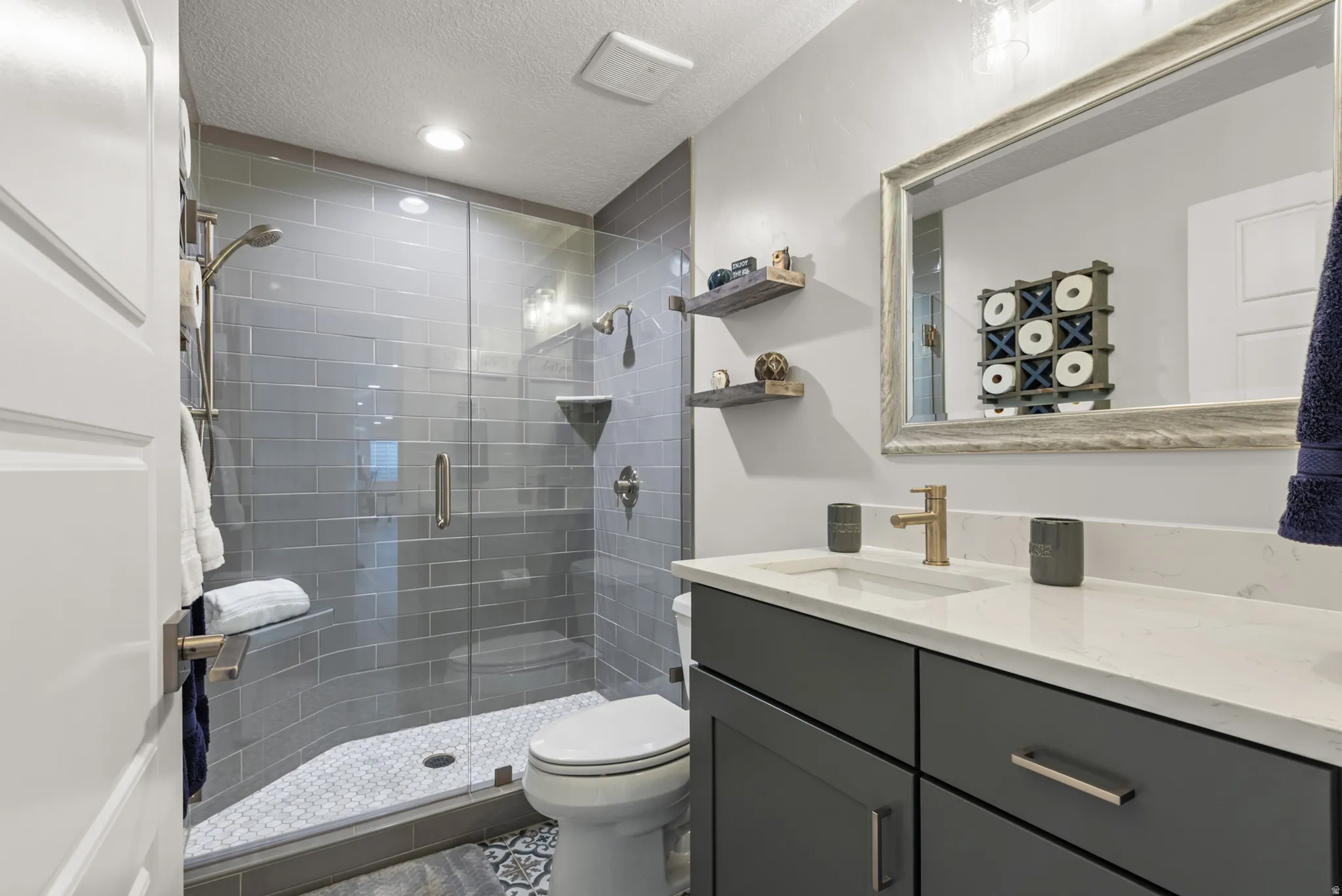 Bathroom featuring a glass-enclosed shower with subway tile surround, white hexagonal mosaic shower floor, and a built-in shower niche