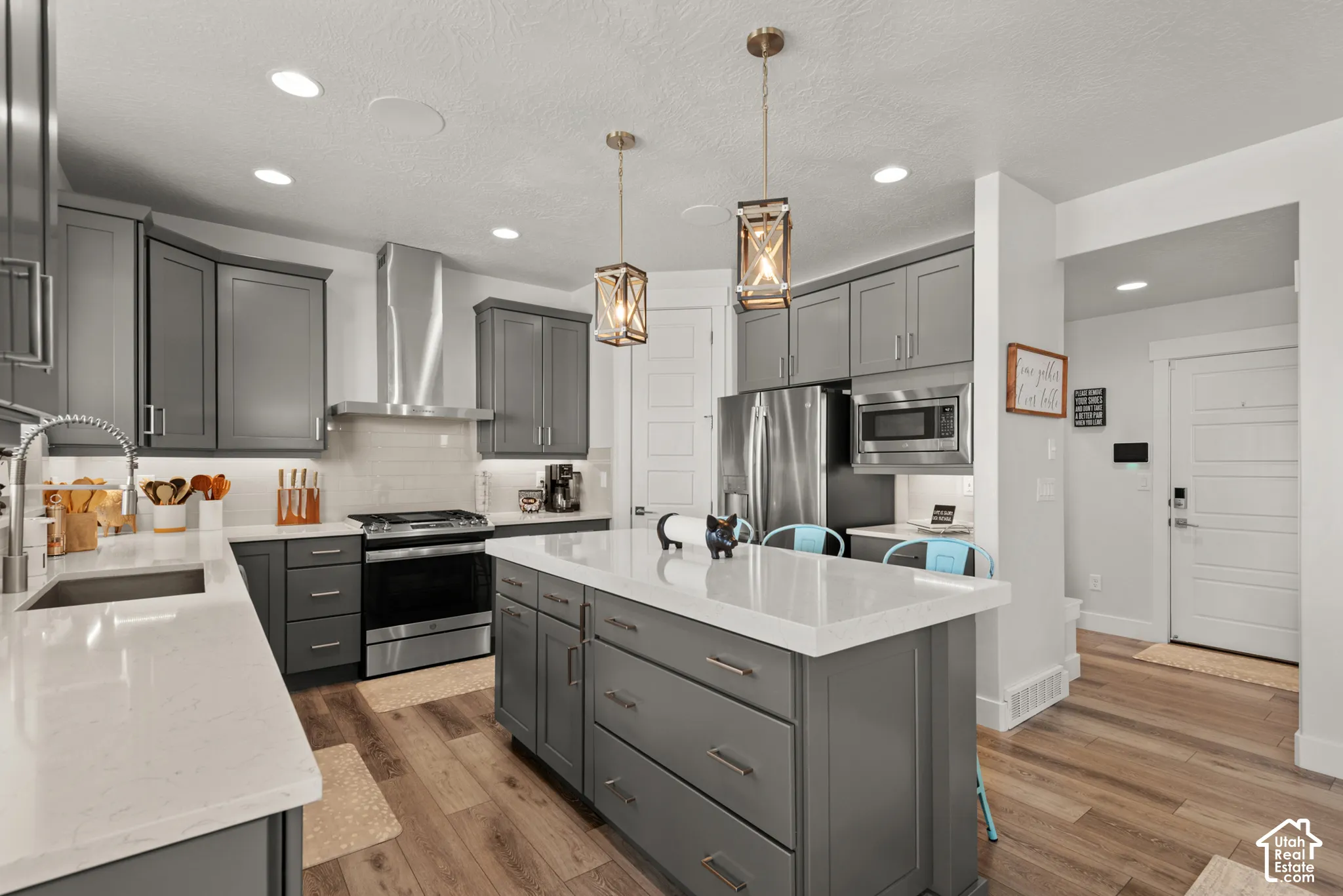 Contemporary kitchen featuring gray shaker cabinetry, stainless steel appliances, and wood-finish flooring