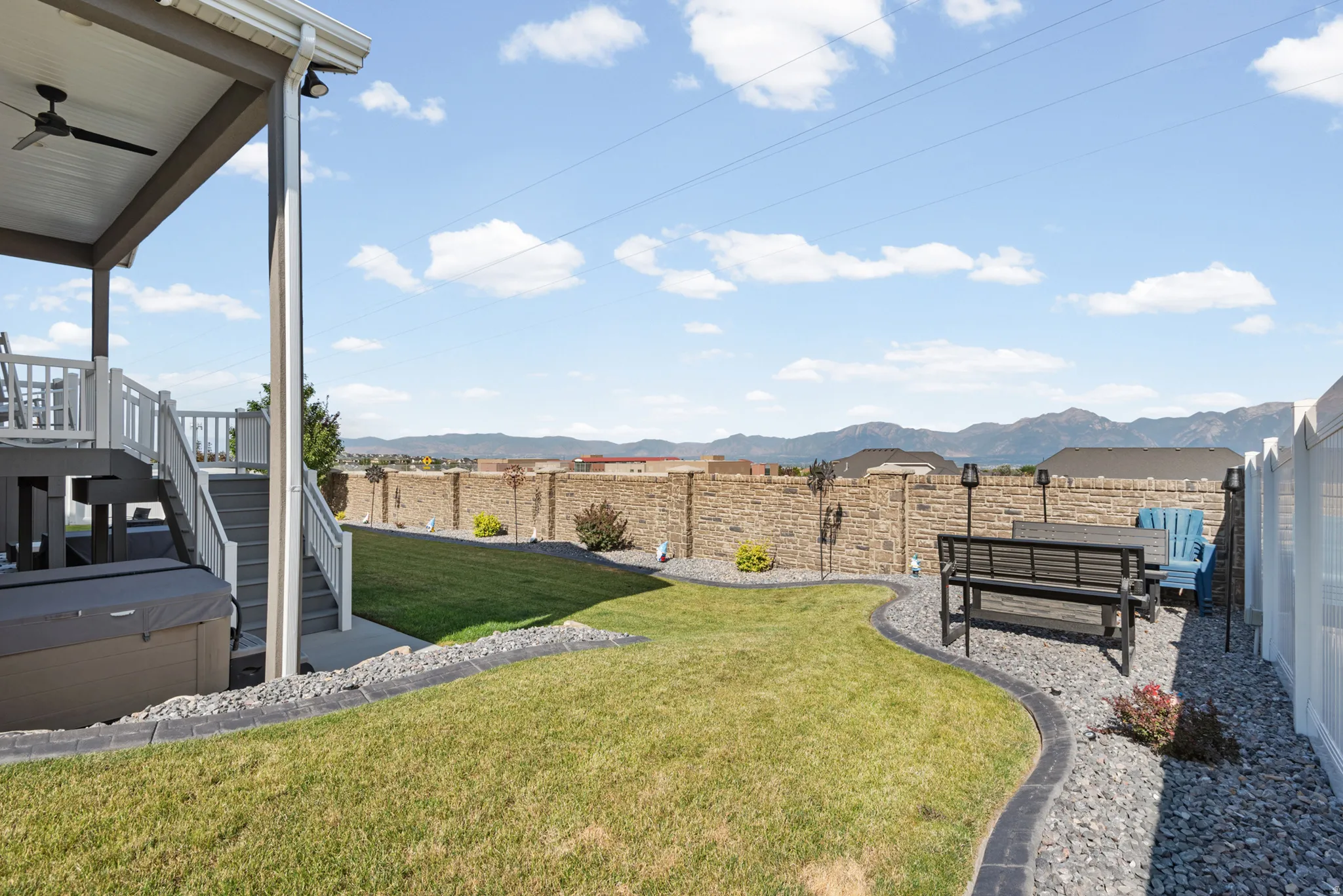 Expansive backyard featuring a green lawn, decorative rock landscaping, and a tiered deck with stairs