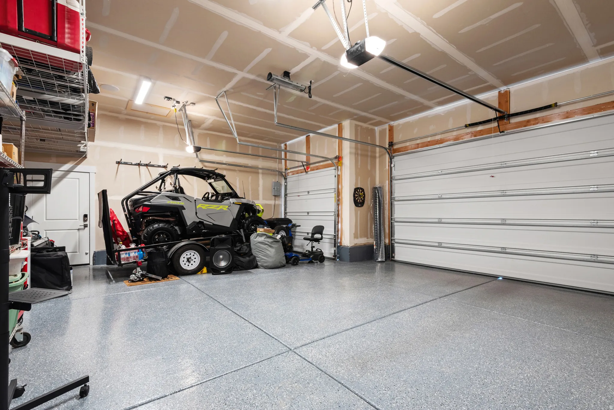 Spacious two-car garage featuring a speckled epoxy floor, two automatic overhead garage doors, and overhead lighting