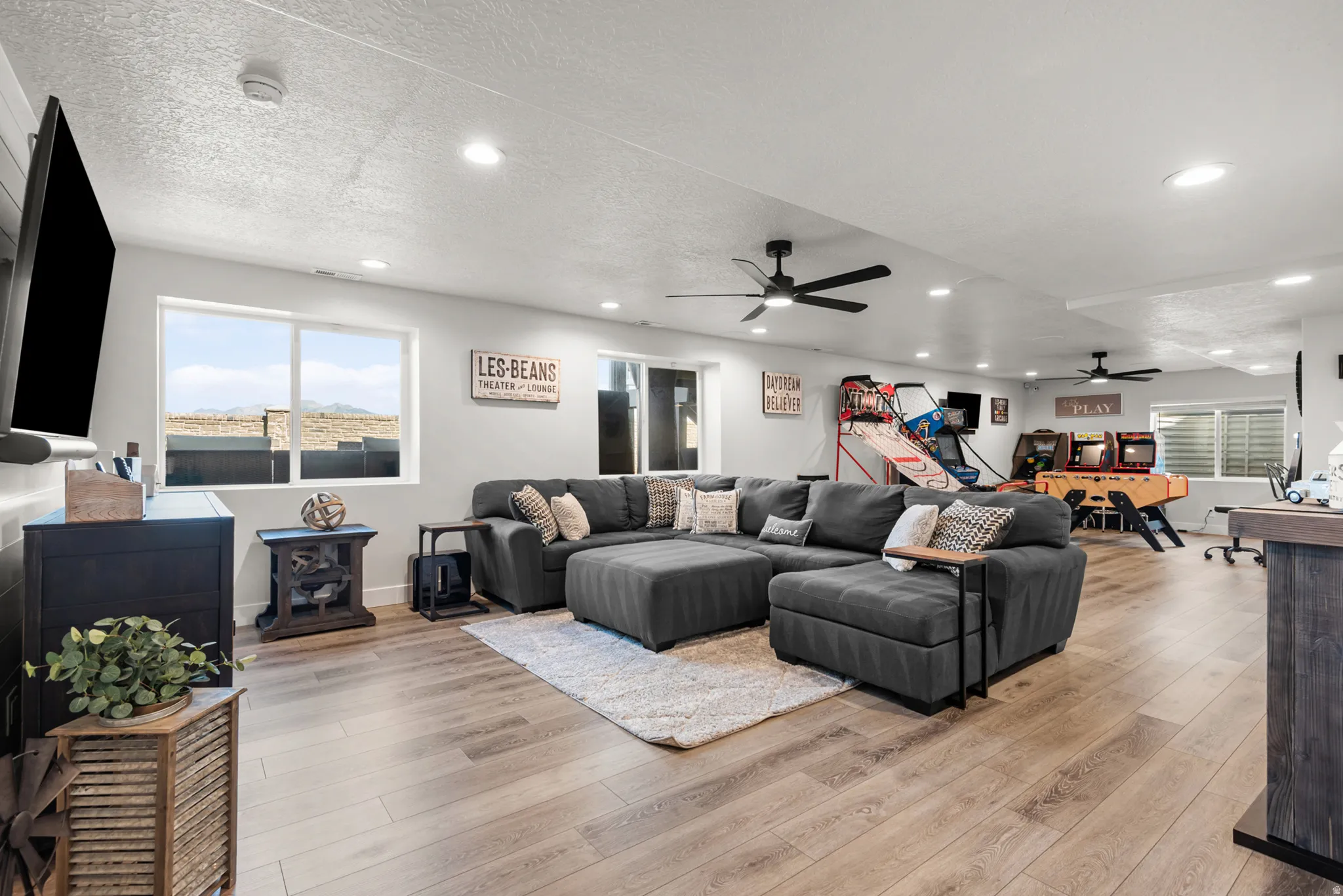Spacious recreation room featuring light wood-finish flooring, recessed lighting, and multiple ceiling fans