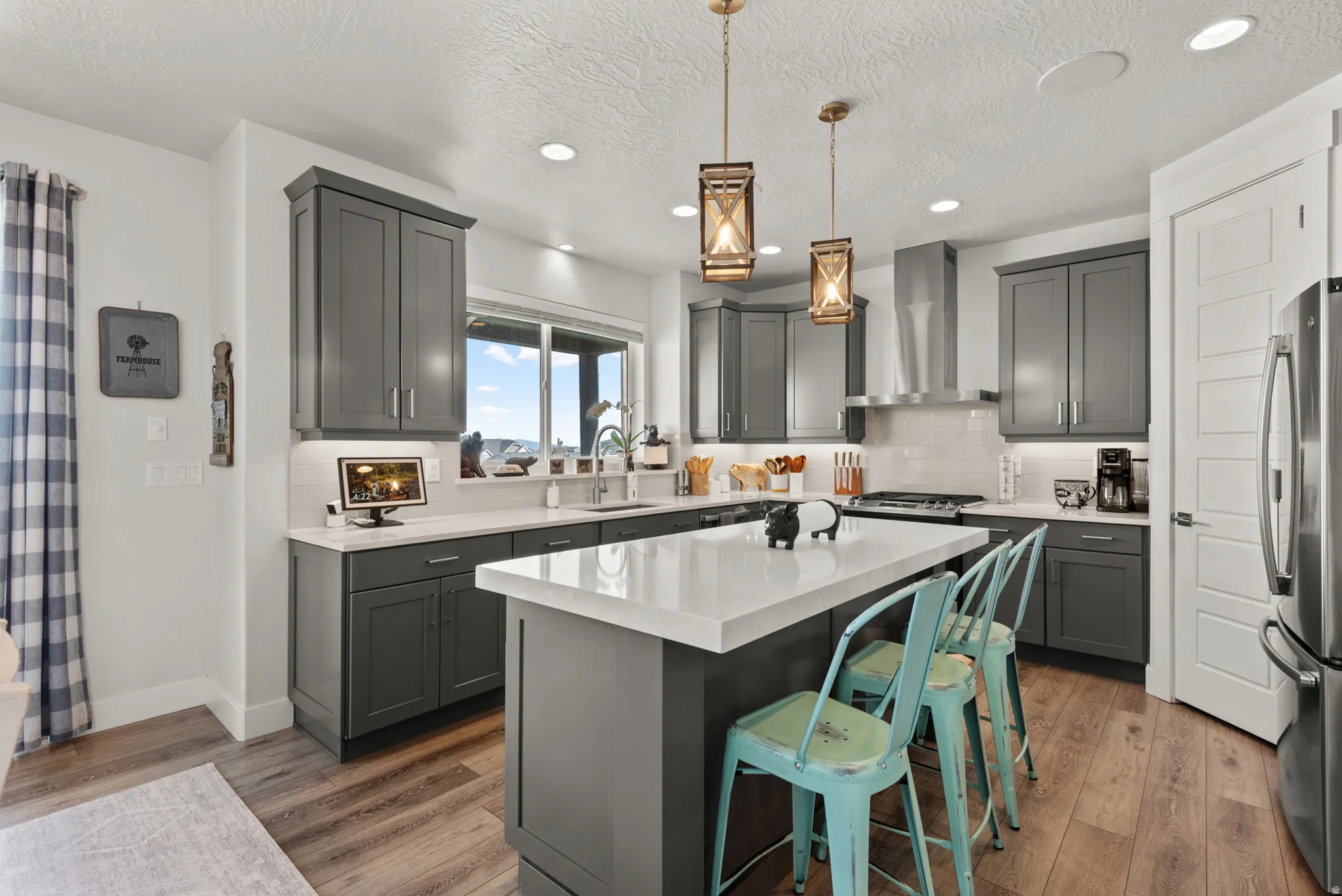 Contemporary kitchen featuring dark gray cabinetry, white countertops, stainless steel appliances, and wood-finish flooring
