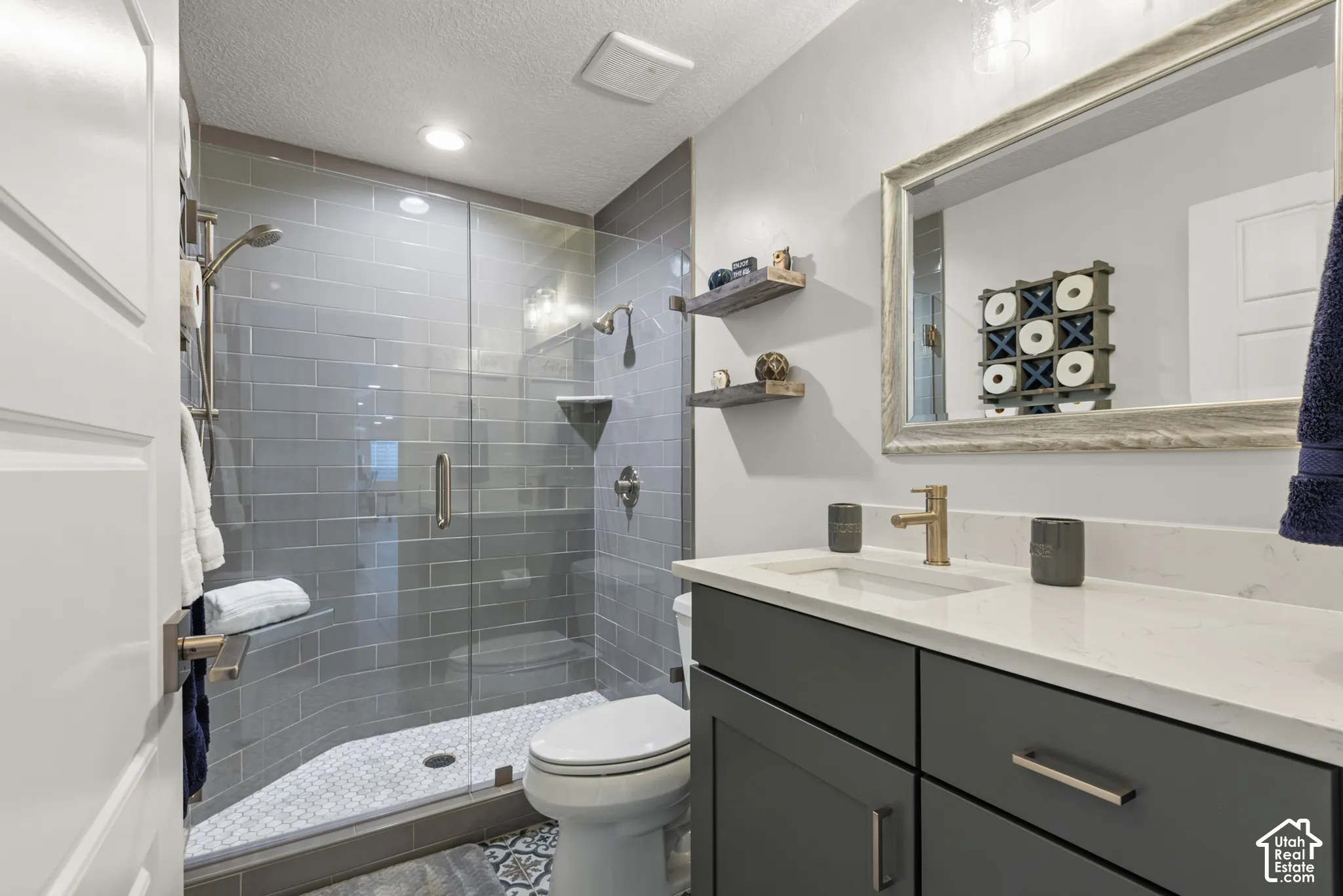 Bathroom featuring a glass-enclosed shower with subway tile surround, white hexagonal mosaic shower floor, and a built-in shower niche