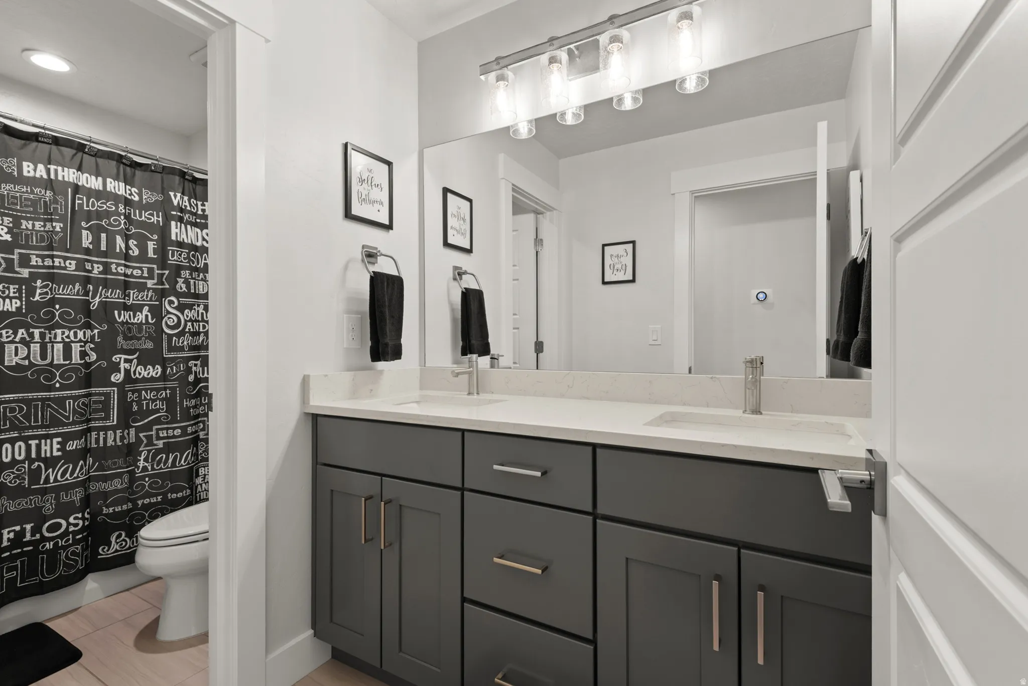 Dual vanity with gray cabinetry, brushed nickel hardware, and light-toned countertops