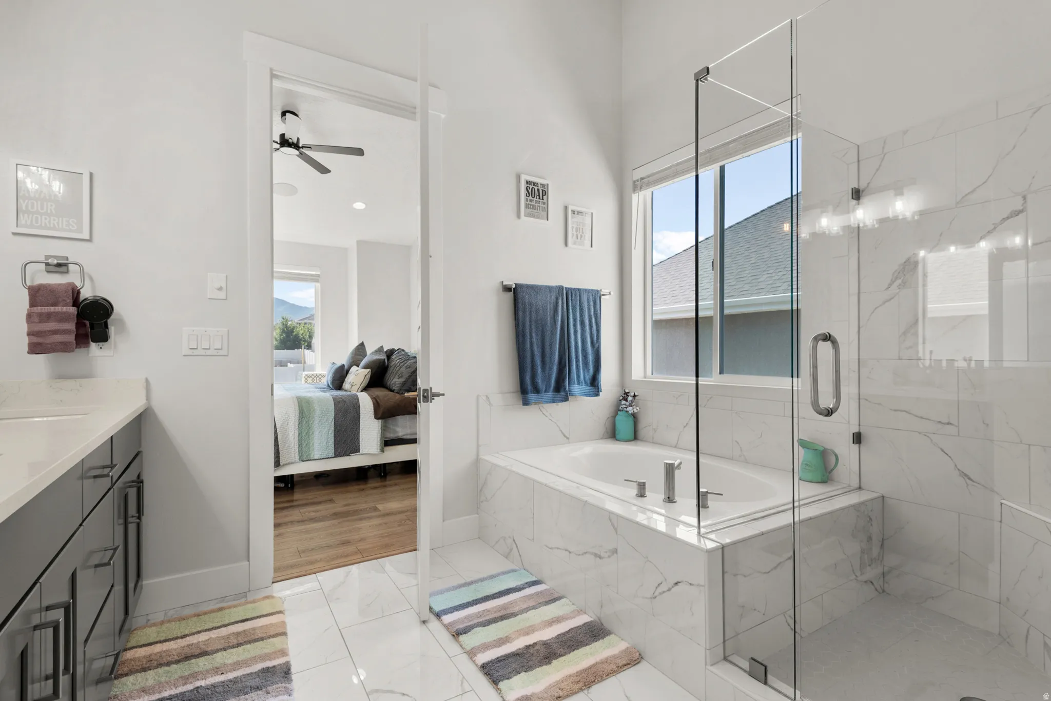 Bathroom featuring a built-in soaking tub, glass-enclosed shower, white tile flooring, and white and gray marbled wall tiling