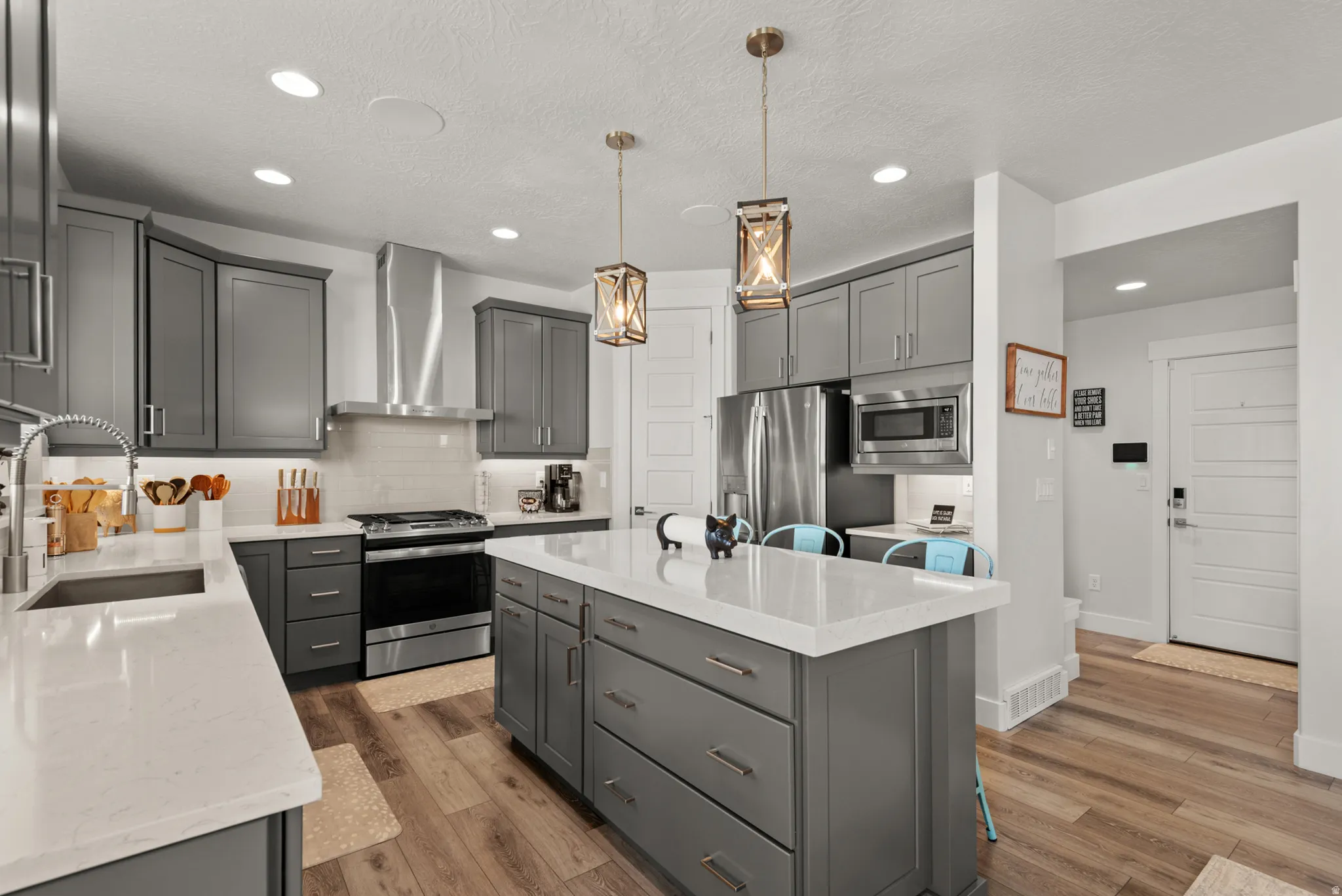 Contemporary kitchen featuring gray shaker cabinetry, stainless steel appliances, and wood-finish flooring