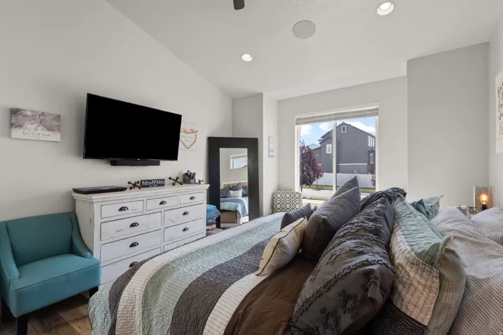 Spacious room featuring vaulted ceilings, recessed lighting, wood-finish flooring, and a large window offering ample light