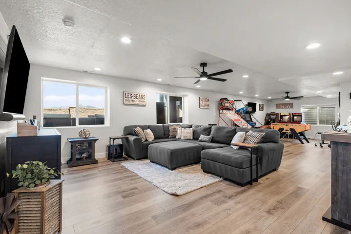 Spacious recreation room featuring light wood-finish flooring, recessed lighting, and multiple ceiling fans