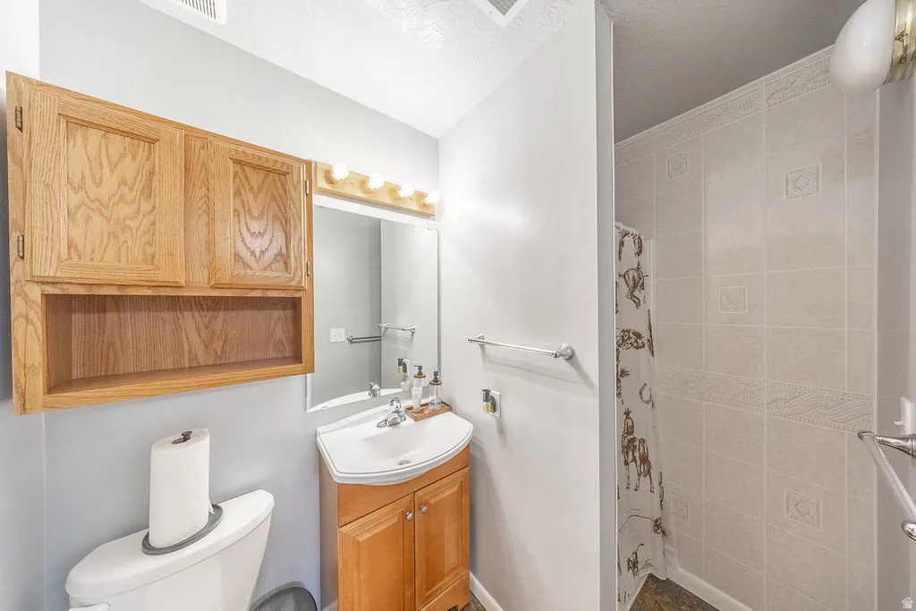 Bathroom featuring a light wood vanity with an integrated sink, a mirrored medicine cabinet with vanity lighting, and a tiled shower enclosure