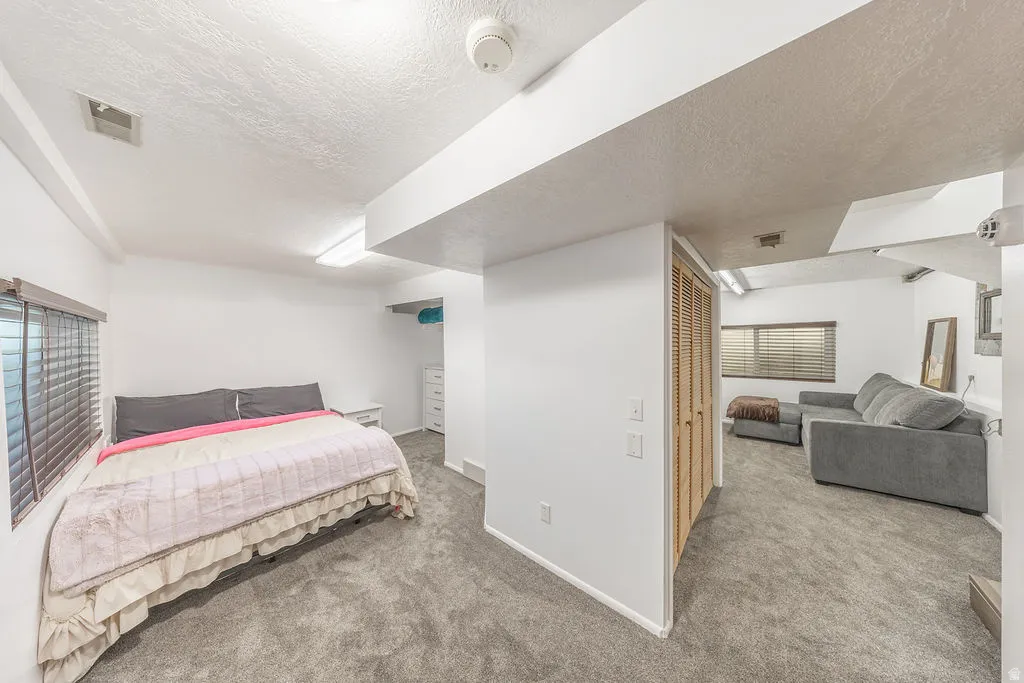 Carpeted room with a window featuring horizontal blinds