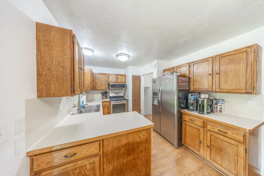 Kitchen featuring wood cabinetry, light-toned countertops, and wood-finish flooring
