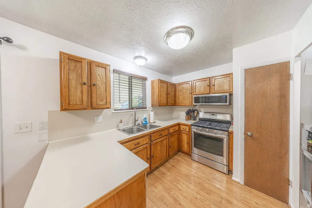 Kitchen featuring wood-finish cabinetry, light-toned countertops, and wood-finish flooring