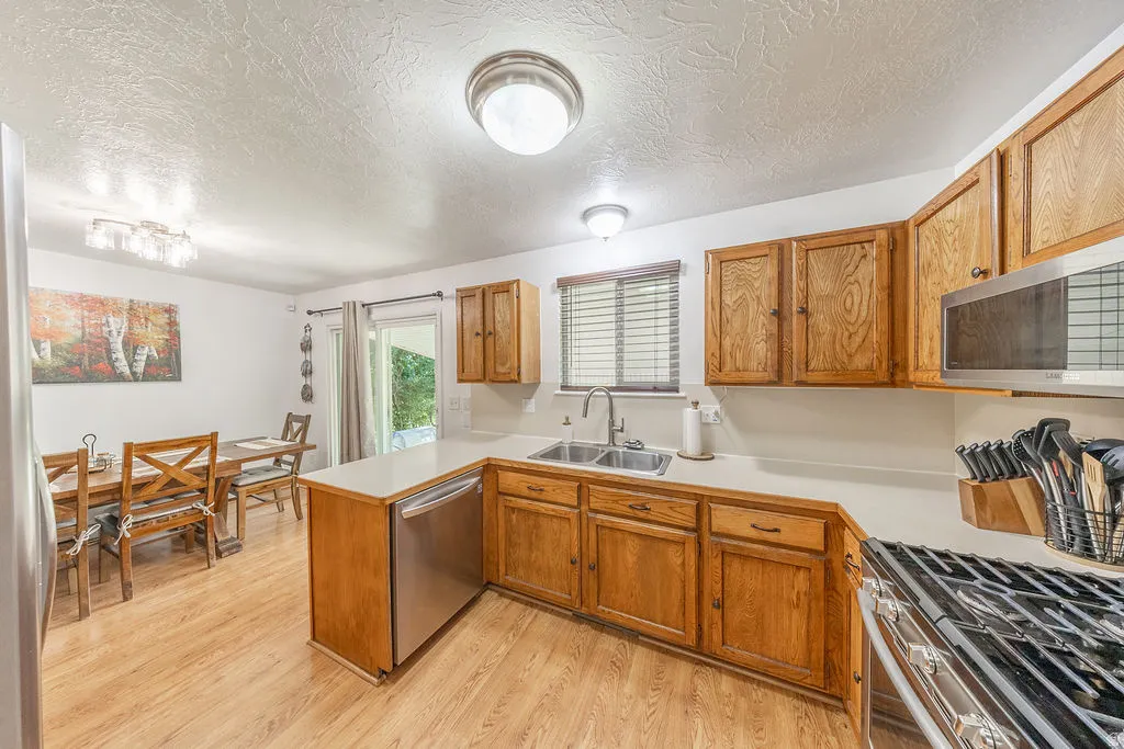 Kitchen featuring wood-finish flooring, wood cabinetry, stainless steel appliances, and a double basin sink
