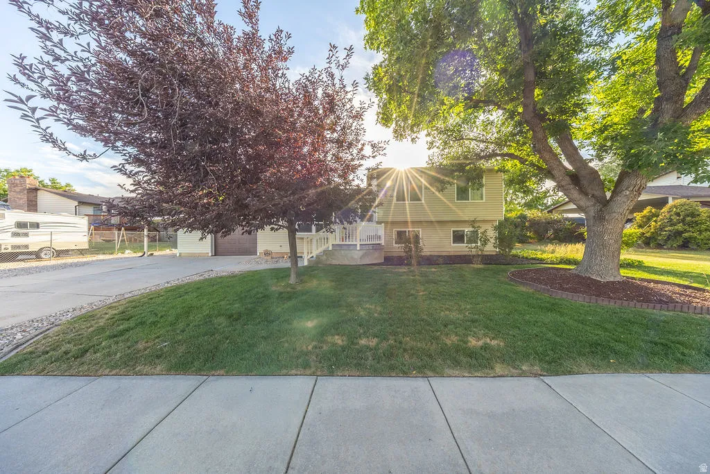 Split-level residence featuring a light-colored exterior, white railing, and a multi-level concrete driveway