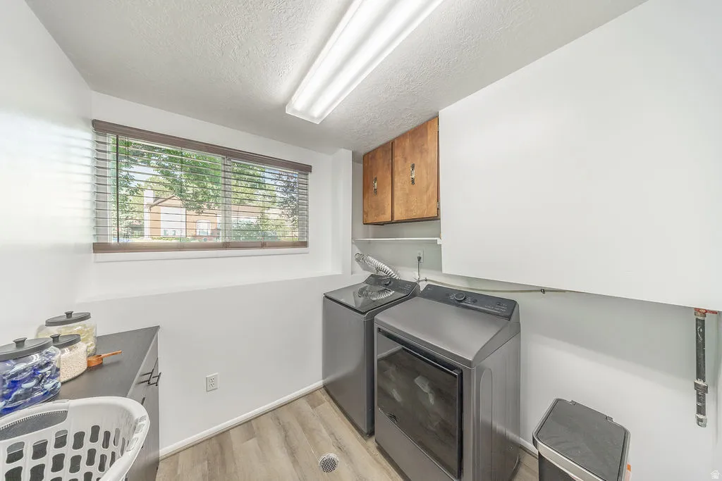 Laundry area featuring wood-finish flooring, a rectangular window with blinds, and built-in upper cabinetry