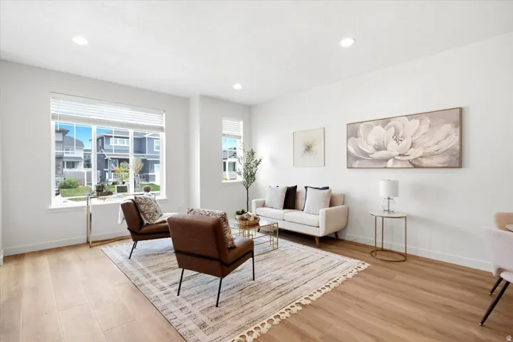 Open concept living space featuring wood-finish flooring, recessed lighting, and large windows with blinds