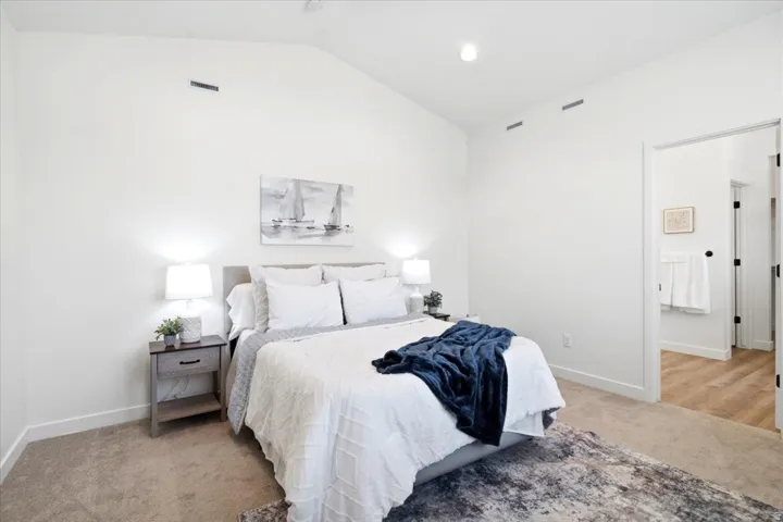 Vaulted ceiling bedroom featuring plush carpet flooring, recessed lighting, and a white trim package