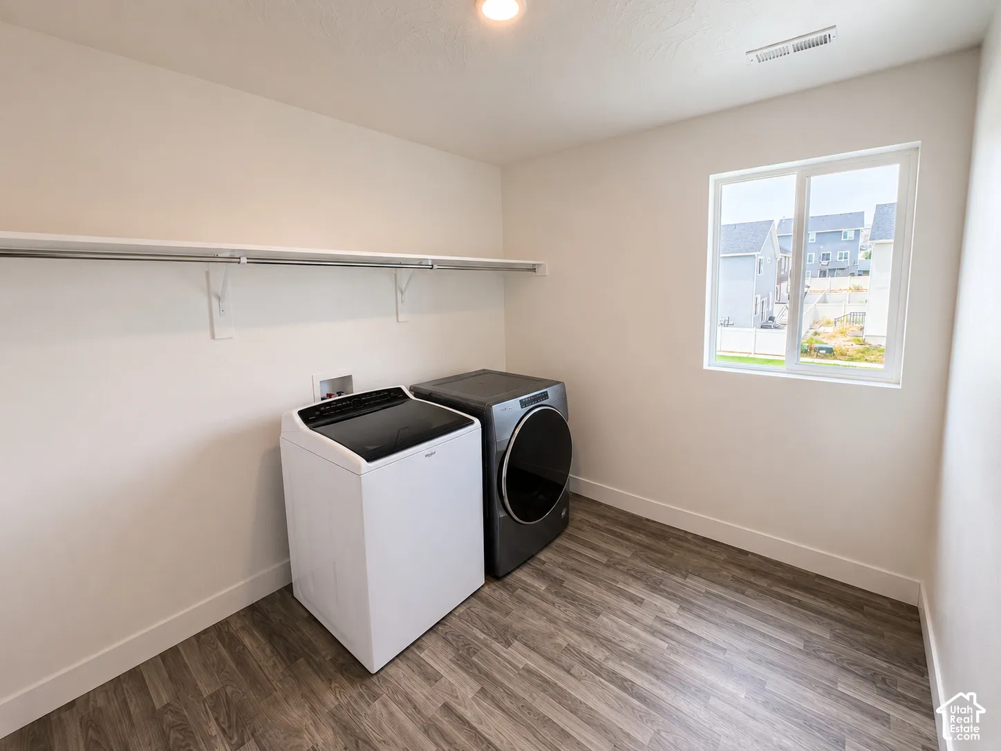 Utility room with wood-finish flooring, a white trim baseboard, and a white framed window