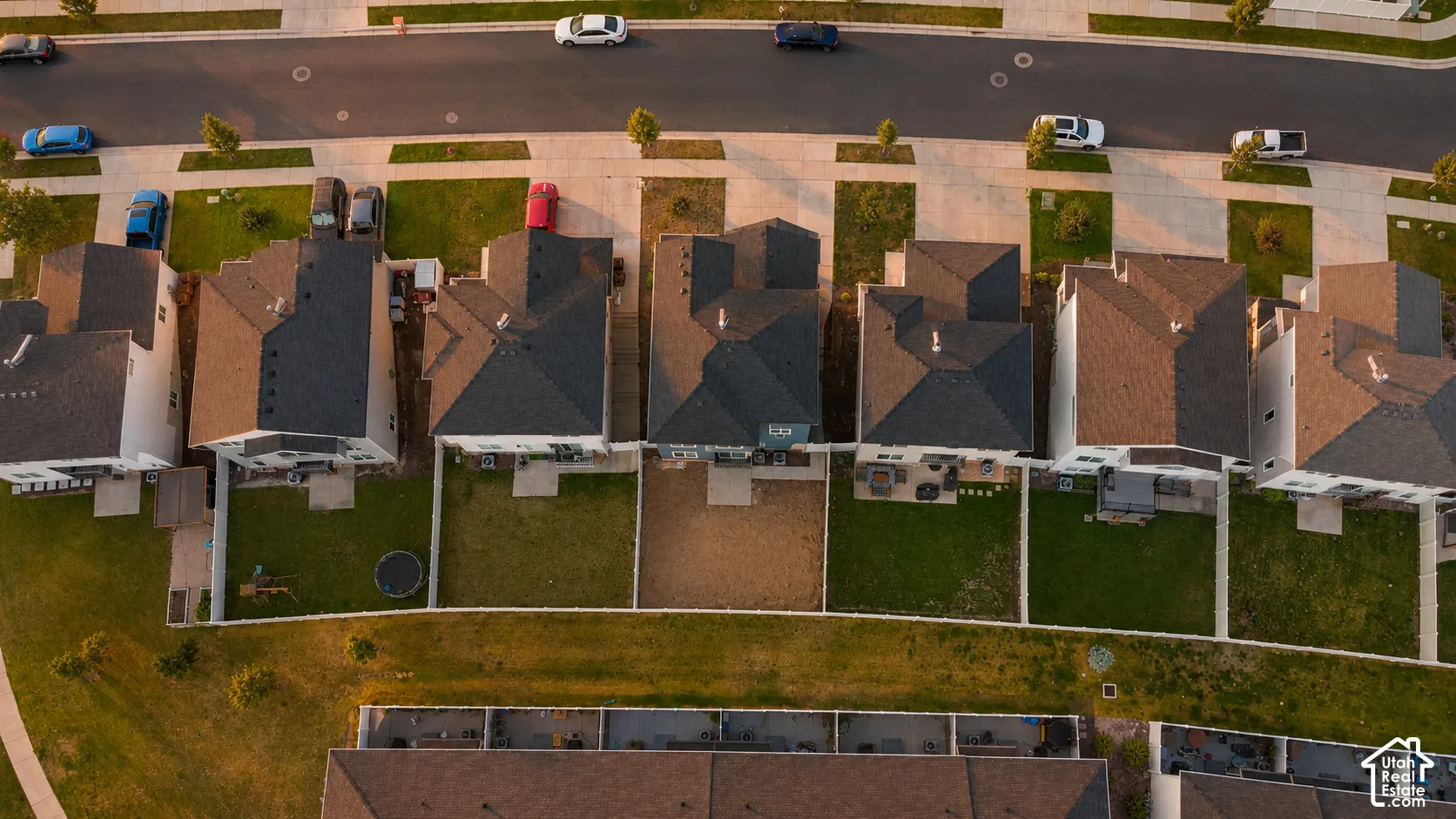 Aerial perspective showcasing a residential street with multiple properties featuring asphalt shingle roofs and fenced backyards