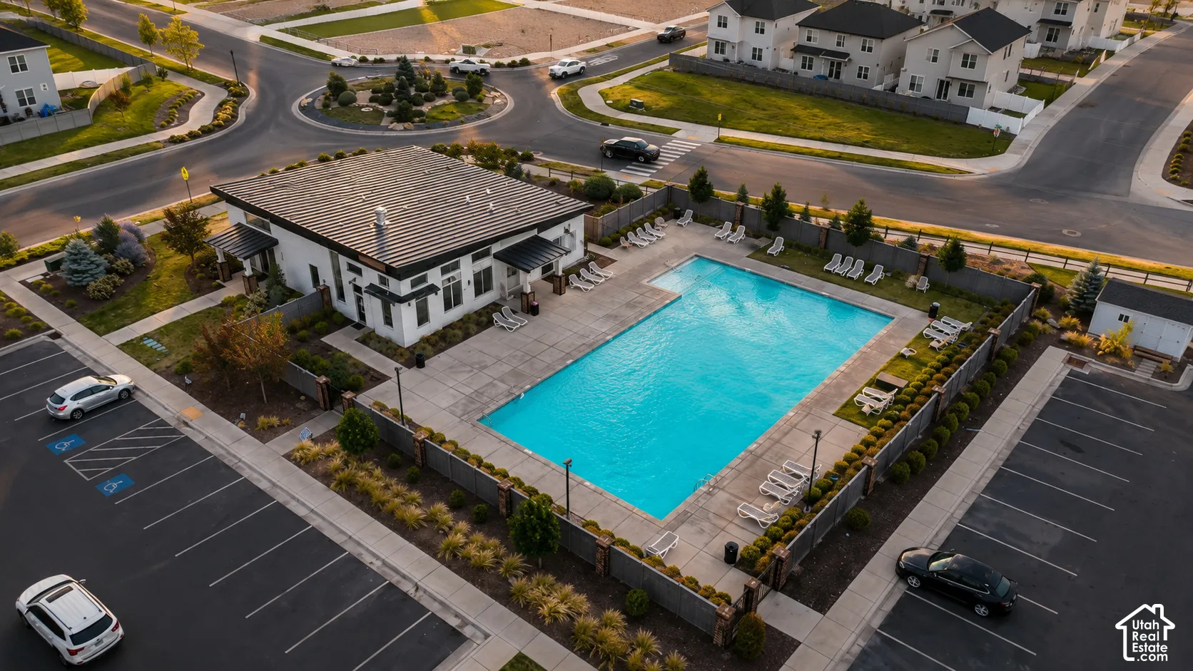 Modern building with a dark metal roof, featuring an adjacent rectangular swimming pool and surrounding paved patio
