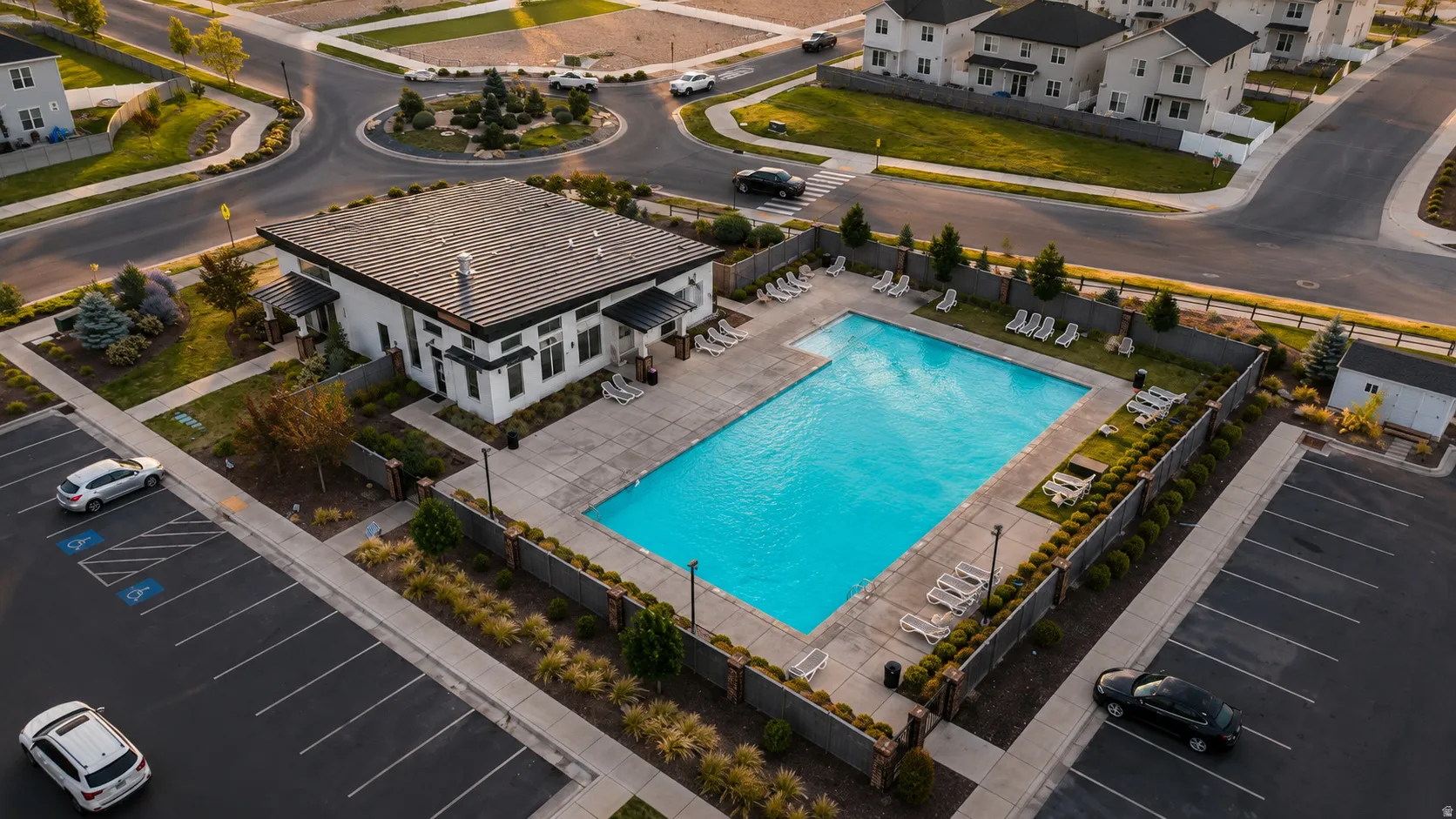 Modern building with a dark metal roof, featuring an adjacent rectangular swimming pool and surrounding paved patio