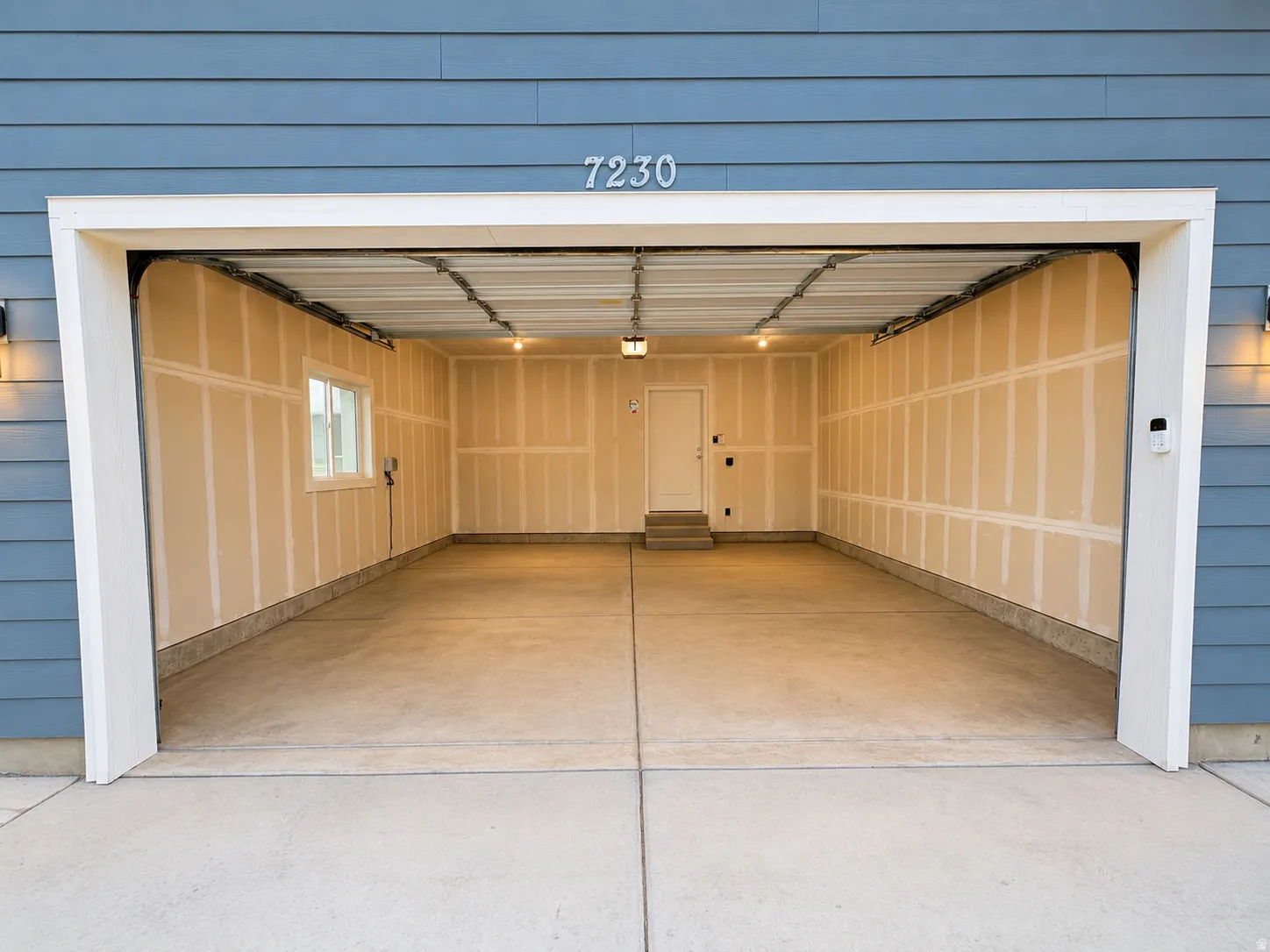 Two-car garage with concrete flooring, a side window, and an interior access door