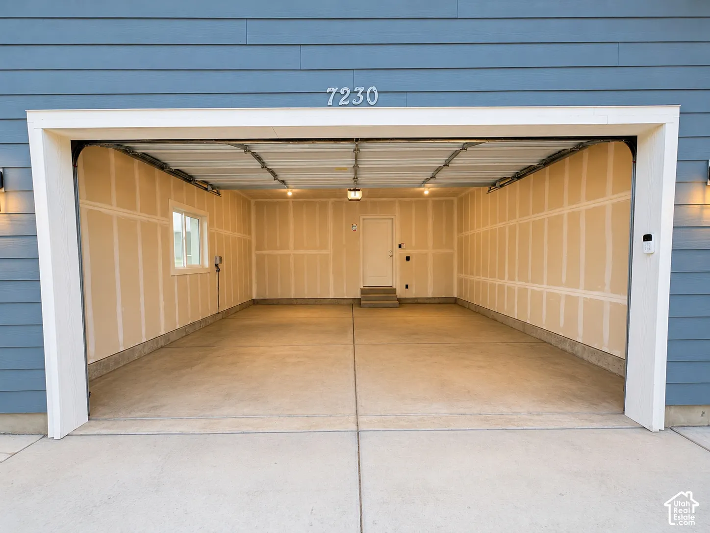 Two-car garage with concrete flooring, a side window, and an interior access door