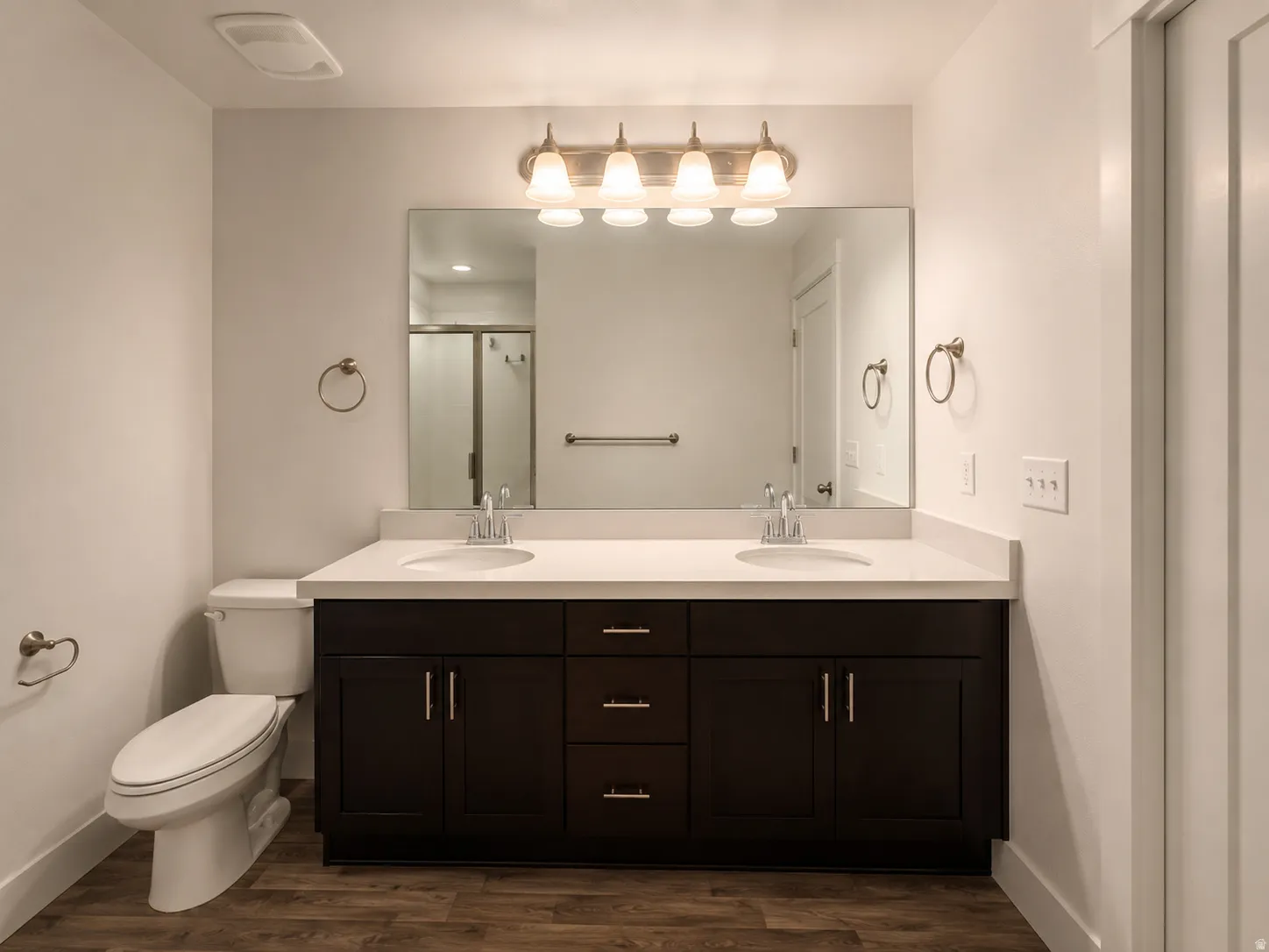 Dual vanity with white solid surface countertop, dark wood-finish cabinetry, and brushed nickel hardware