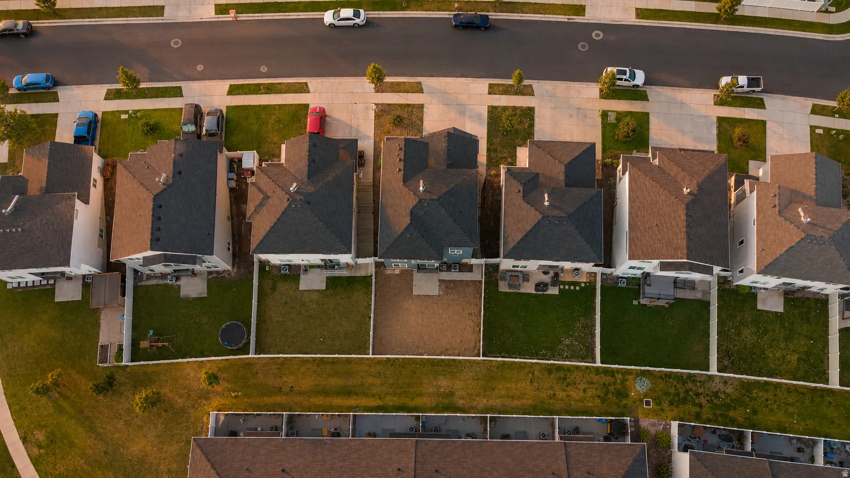 Aerial perspective showcasing a residential street with multiple properties featuring asphalt shingle roofs and fenced backyards