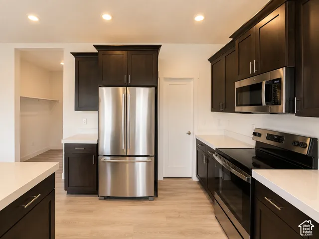 Kitchen featuring dark wood-finish cabinetry with brushed nickel hardware, white countertops, and stainless steel appliances