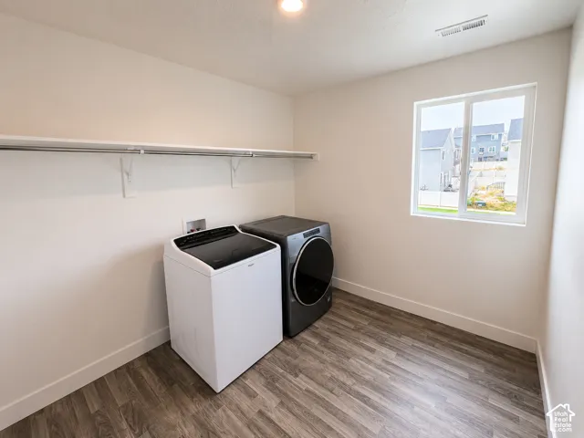 Utility room with wood-finish flooring, a white trim baseboard, and a white framed window