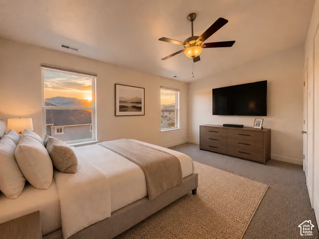 Spacious bedroom featuring dual windows, vaulted ceiling, and a ceiling fan with integrated lighting