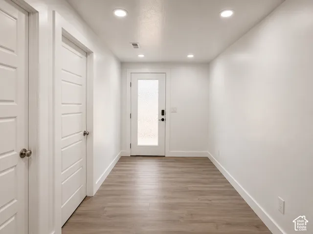Hallway featuring wood-finish flooring, recessed lighting, and a white interior door with frosted glass paneling