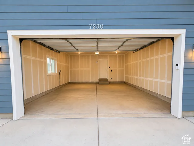 Two-car garage with concrete flooring, a side window, and an interior access door