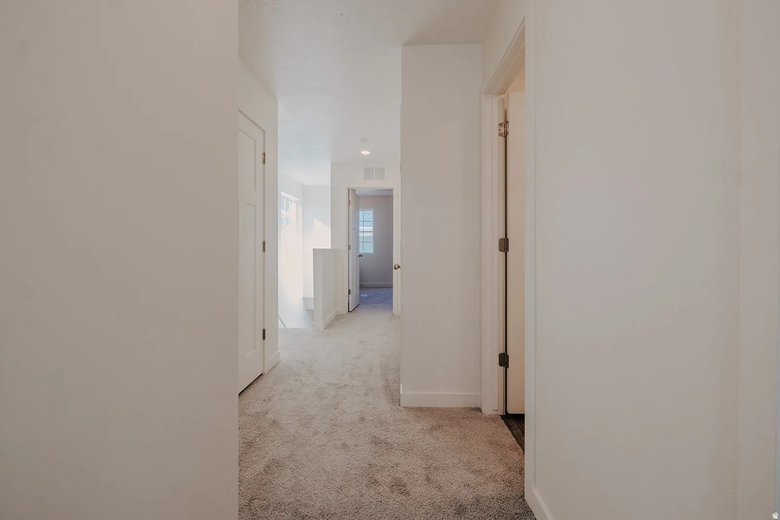 Carpeted hallway with white walls, white trim, recessed lighting, and white panel doors
