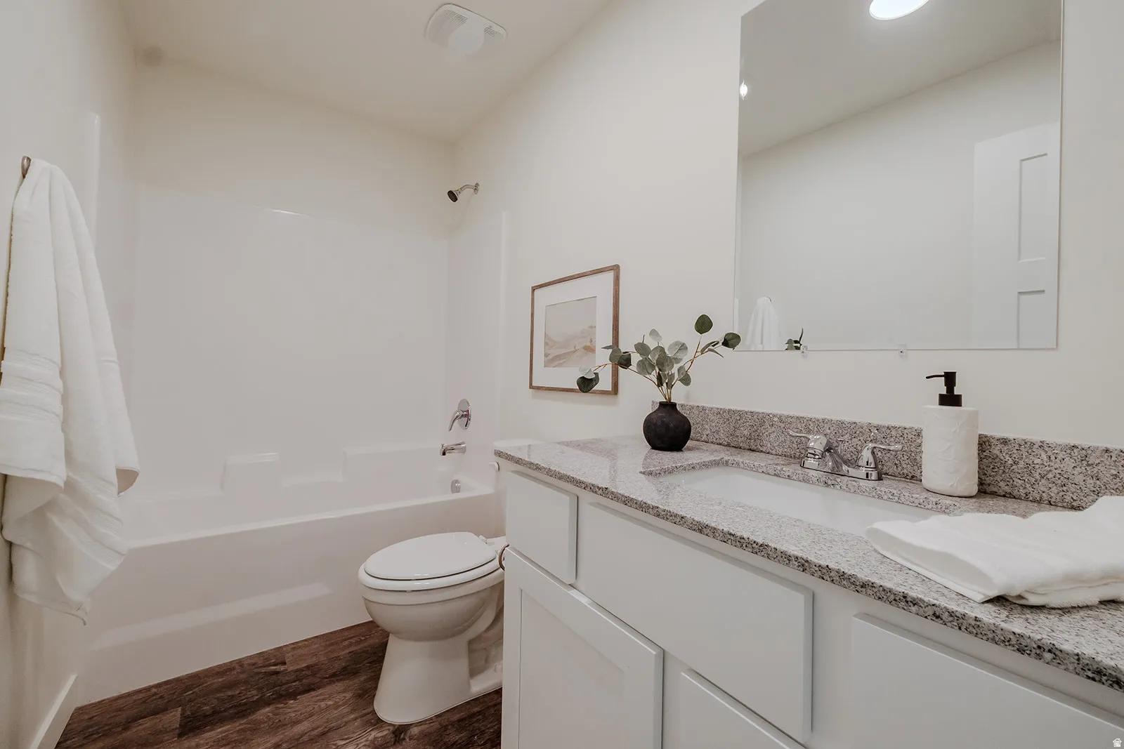 Bathroom featuring a white vanity with a light-colored speckled countertop, an integrated sink, and chrome fixtures