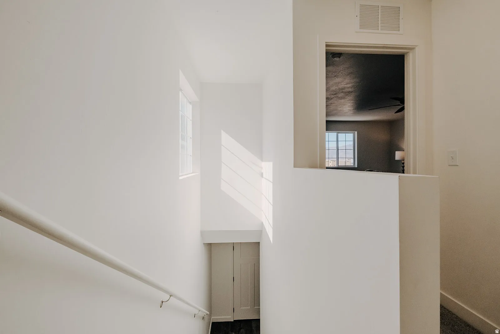 Staircase landing featuring a white handrail, recessed wall alcove, and neutral wall tones