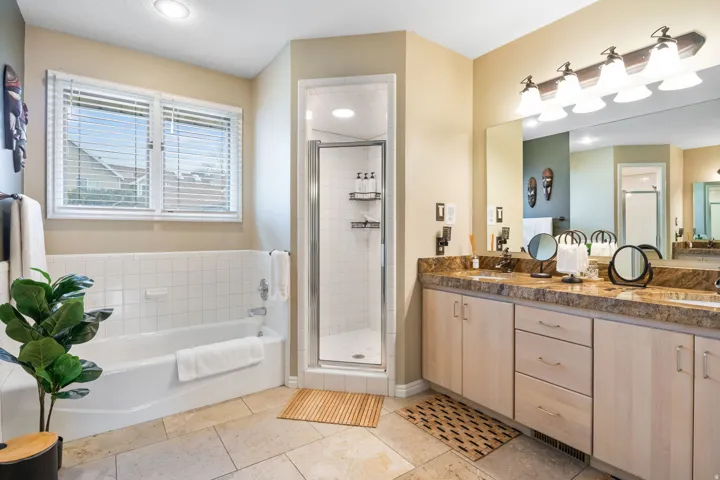 Full bath with a shower stall, a bath, double vanity, and light tile patterned flooring