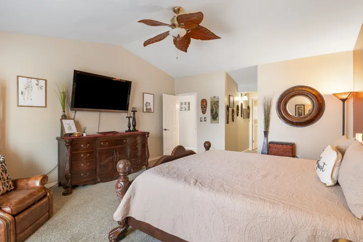Bedroom featuring vaulted ceiling, carpet, and a ceiling fan