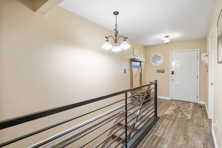 Corridor with a chandelier, an upstairs landing, and light wood-type flooring