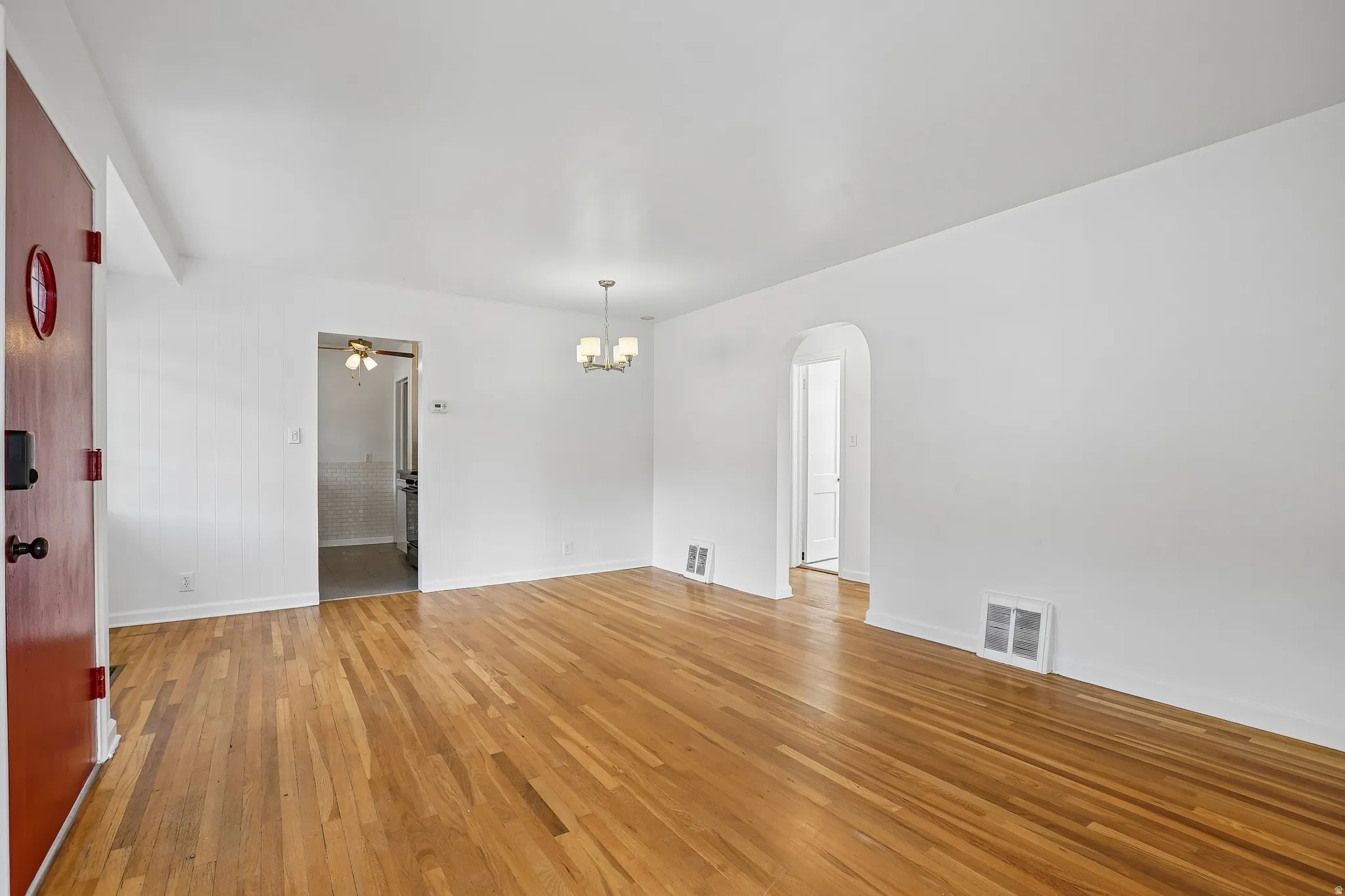 Spacious room with wood-finish flooring and a central chandelier