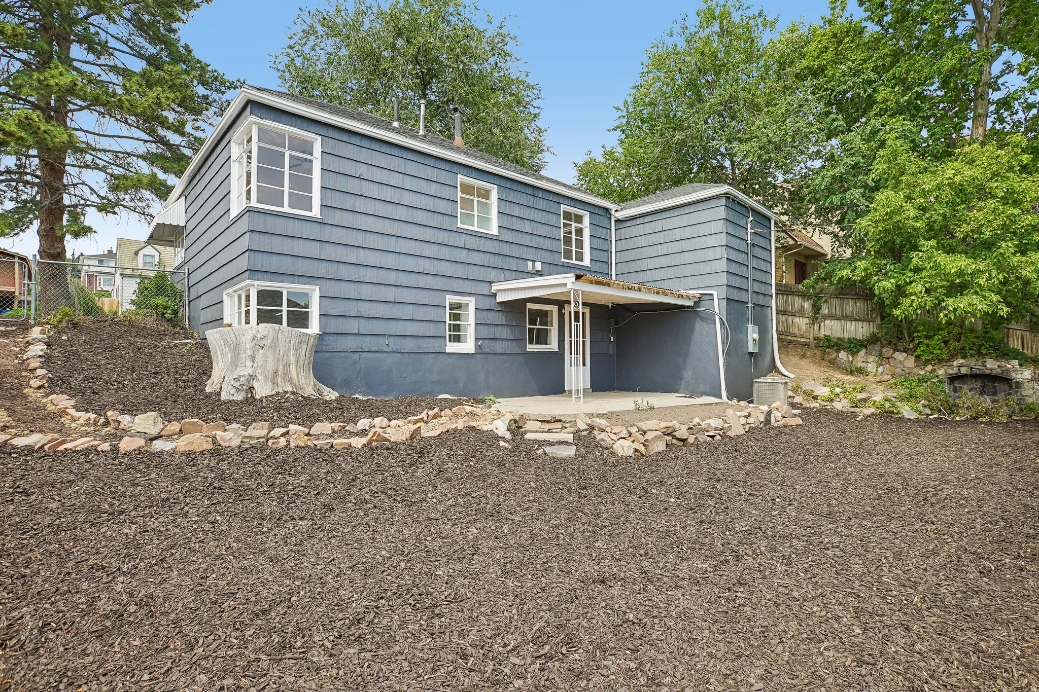Rear exterior featuring blue siding, white-framed windows, and a covered concrete patio