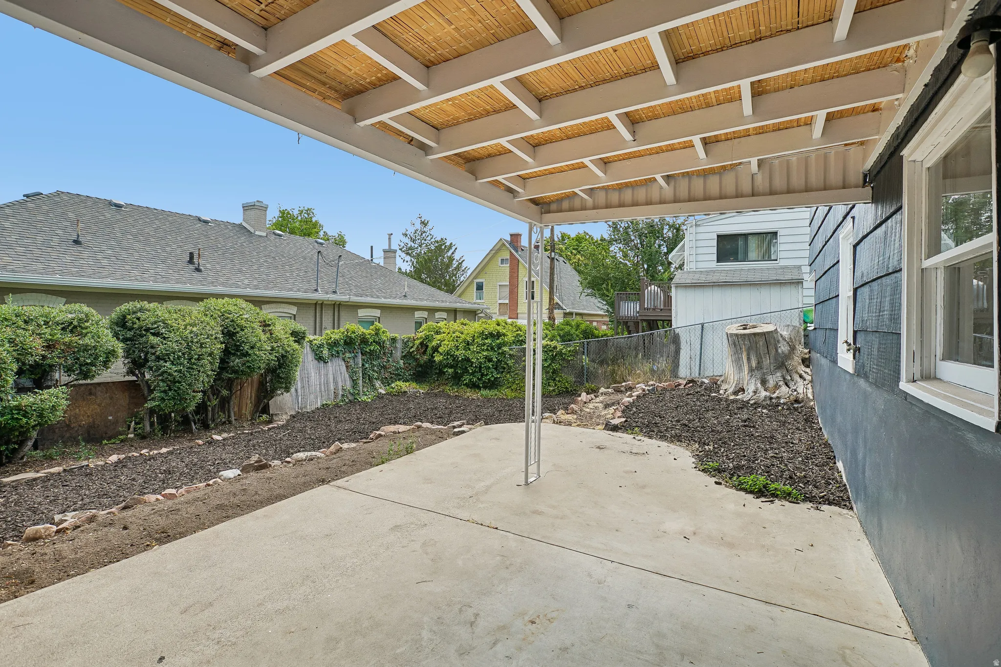 Covered patio area with concrete flooring, accented by a decorative wooden slat ceiling